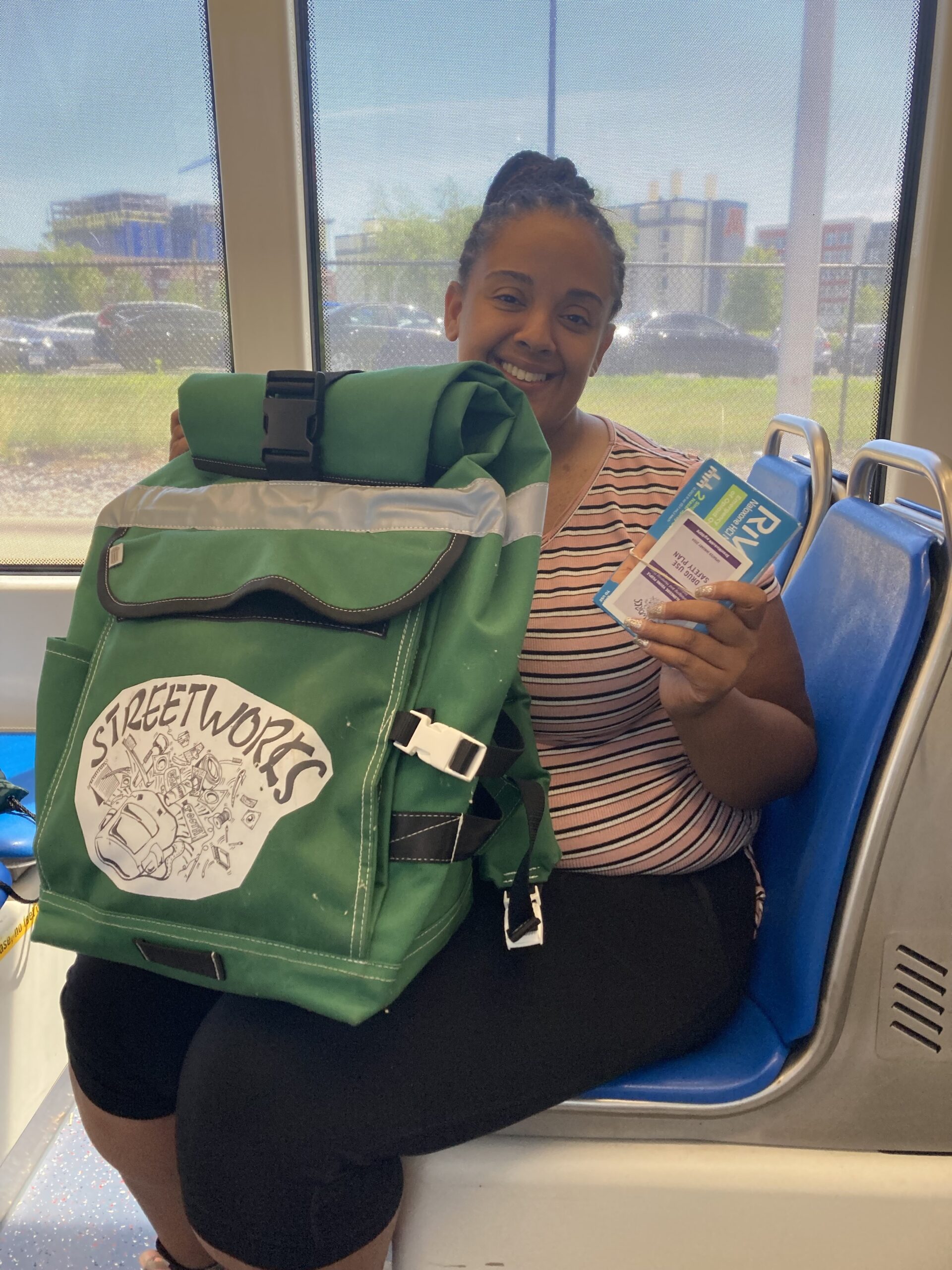 Photo of Britney smiling and holding a StreetWorks GreenBag and nasal naloxone